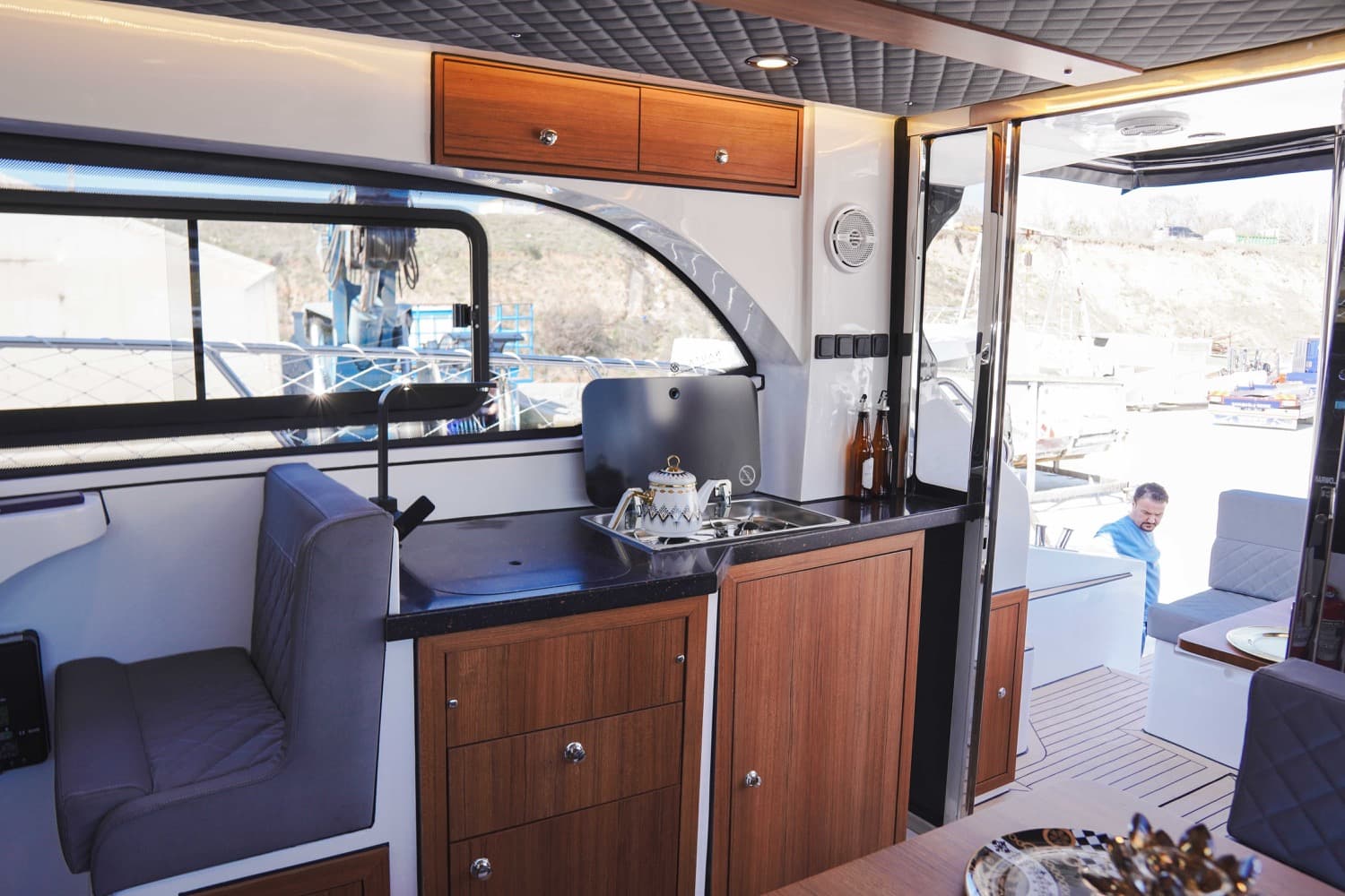 Nauta Poseidon 35 kamaralı fiber teknenin iç mekânı: tik dolaplı mutfak, ocak, lavabo ve salon oturma grubu